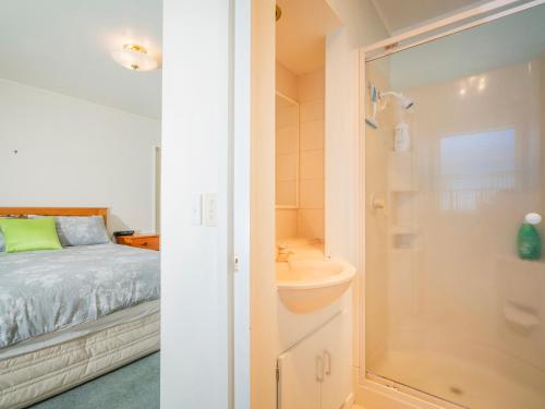 - une chambre et une salle de bains avec un lit et un lavabo dans l'établissement The Bach - Whangamata Holiday Home, à Whangamata
