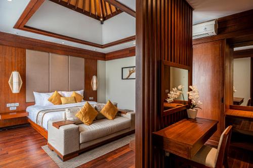 a bedroom with a bed with a couch and a table at Tanadewa Villas & Spa in Nusa Dua
