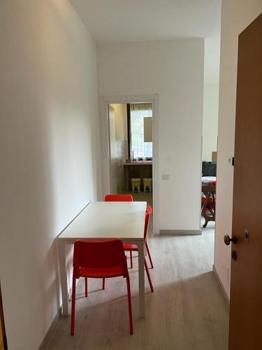 a white table and two red chairs in a room at Senza Pensieri via Viviani in Crema