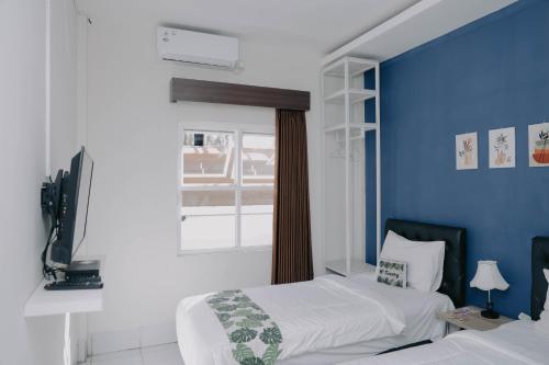 - une chambre avec 2 lits et un mur bleu dans l'établissement Tienery Guesthouse, à Tanjungkarang