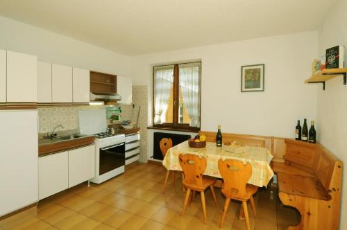 eine Küche mit einem Tisch und Stühlen sowie eine Küche mit weißen Schränken in der Unterkunft Casa Katya in Pracorno di Rabbi