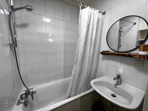 ein Badezimmer mit einem Waschbecken, einer Badewanne und einem Spiegel in der Unterkunft Aiguille Verte 28 - Studio avec vue in La Clusaz