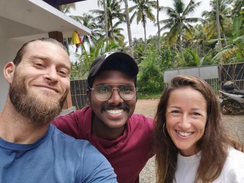 two men and a woman posing for a picture at Munroe Coconut Homestay in Munroe Island