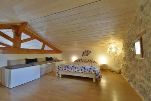 een slaapkamer met een bed en een bank in een kamer bij Gîte L'Insouciant - Domaine la Rose des vents in Castelnau-sur-lʼAuvignon
