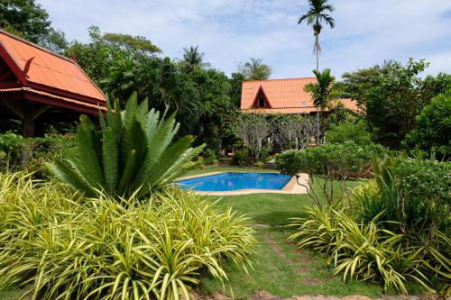 a garden with a swimming pool and a house at Piman Pu in Ko Jum