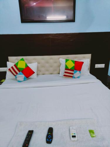 a white bed with two remote controls on it at Hotel APJ GRAND in Faridabad