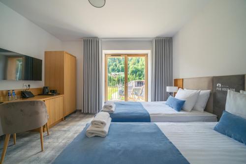 um quarto de hotel com duas camas e uma secretária em Willa Pod Kolejką em Szczawnica