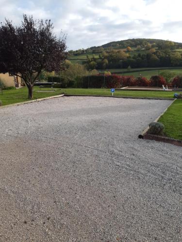 a large gravel driveway with a tree and grass at L OLIVIER DE ST LEGER in Château