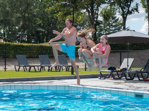 een man en twee kinderen die in een zwembad springen bij TopParken – Recreatiepark de Wielerbaan in Wageningen