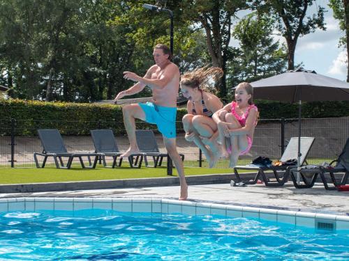 a man and two children jumping into a swimming pool at Recreatiepark de Wielerbaan in Wageningen