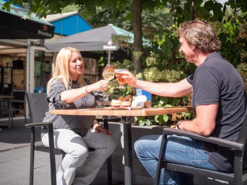 un hombre y una mujer sentados en una mesa bebiendo vino en TopParken – Recreatiepark de Wielerbaan, en Wageningen