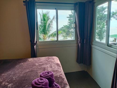 Habitación con ventana y toallas moradas en una cama. en Cliff View Bungalows en Ko Chang