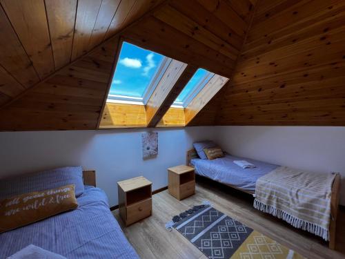 an attic bedroom with two beds and two windows at Paradise Resort in Miercurea-Ciuc