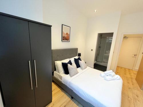 a bedroom with a large bed and a black cabinet at Stunning mill apartment near to city centre and Etihad stadium! in Manchester