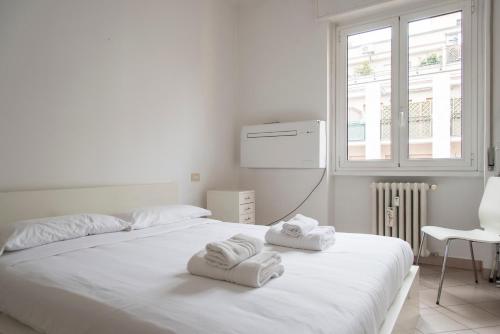a white bedroom with two towels on a bed at YouHosty - Metauro 4 in Milan