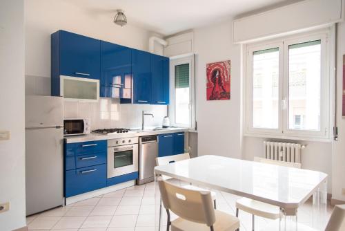 a kitchen with blue cabinets and a table and chairs at YouHosty - Metauro 4 in Milan