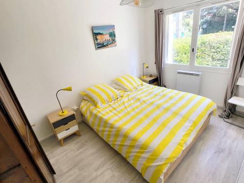 une chambre avec un lit jaune et blanc et une fenêtre dans l'établissement Charmant T2 à Six-Fours - Terrasse et Proximité Plage - Résidence Sécurisée - FR-1-316-232, à Six-Fours-les-Plages