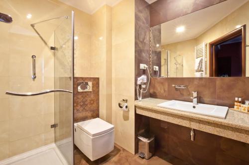 a bathroom with a toilet and a sink and a shower at Artis Hotel & Spa in Zamość