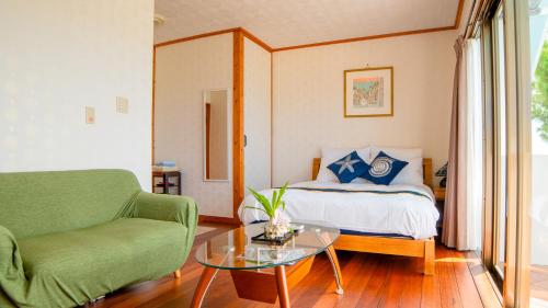 a bedroom with a bed and a couch and a table at Sunset Beach House in Onna