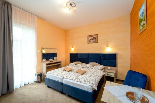 a bedroom with a blue bed and a desk and a window at Penzion Josu in Zuberec