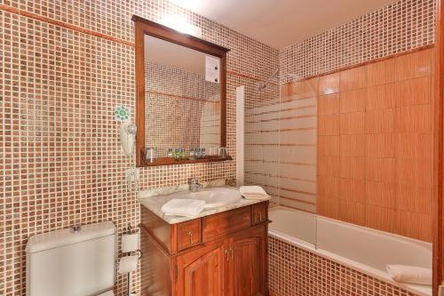 a bathroom with a sink and a tub and a mirror at Hôtel Playa in Saint-Tropez