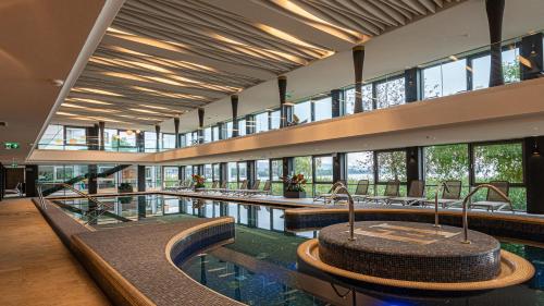a large building with a large pool of water with windows at Hotel Helikon, Keszthely in Keszthely