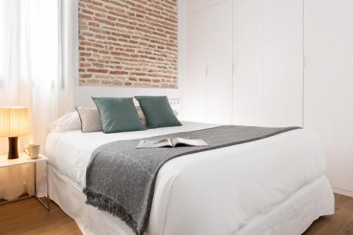 sypialnia z białym łóżkiem z ceglaną ścianą w obiekcie One&lux Puerta Osario w Sewilli