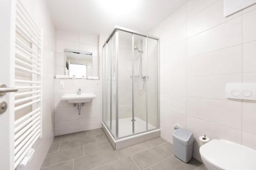 ein weißes Bad mit einer Dusche und einem Waschbecken in der Unterkunft Hotel garni Milseburg in Hilders