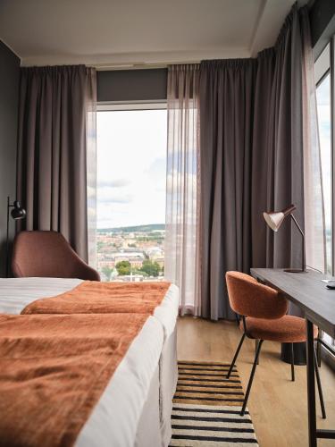 a hotel room with two beds and a desk and a window at Quality Hotel Match in Jönköping