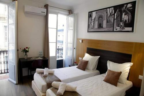 Hotel de la Poste في Kasbah: غرفة فندقية بسريرين ومكتب