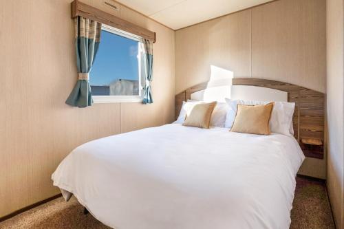 a bedroom with a large white bed with a window at Waterside, Thorpe Park Cleethorpes Static Caravan in Cleethorpes