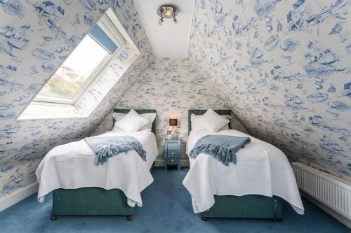 Duas camas num quarto com papel de parede azul e branco em The luxury Beach property - Oceanbreeze em Sandgate
