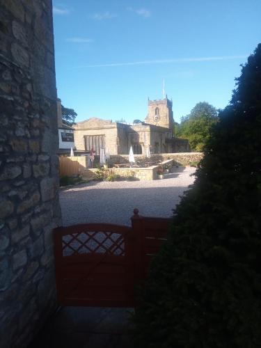 a gate to a building with a church in the background at Charming, wonderfully cosy one bedroom apartment in Giggleswick