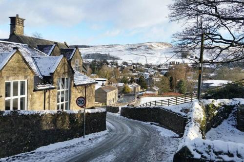 a snow covered street in a village with houses at Charming, wonderfully cosy one bedroom apartment in Giggleswick