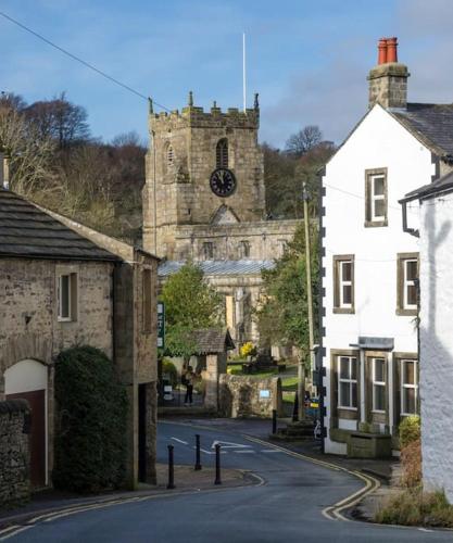 an old building with a clock tower on a street at Charming, wonderfully cosy one bedroom apartment in Giggleswick