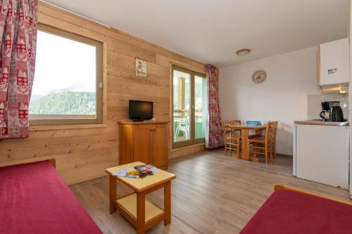 Il comprend une cuisine et un salon avec une table. dans l'établissement Résidence Capfun Couleurs Soleil, Oz en Oisans, à Oz