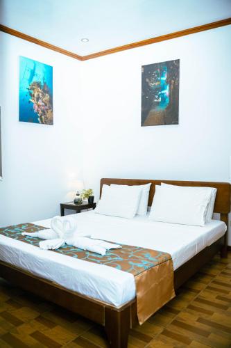 a bedroom with a large bed with white sheets at DiveGurus Boracay Beach Resort in Boracay