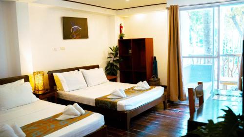a hotel room with two beds and a window at DiveGurus Boracay Beach Resort in Boracay
