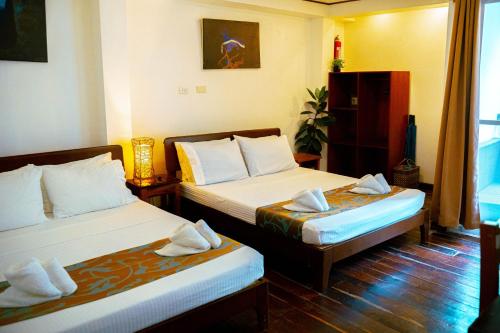 a hotel room with two beds with towels at DiveGurus Boracay Beach Resort in Boracay