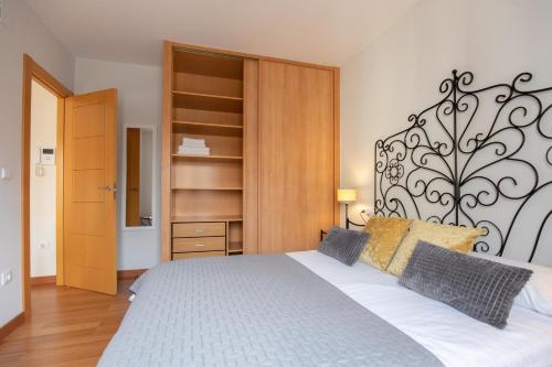 ein Schlafzimmer mit einem weißen Bett mit einem schwarzen Kopfteil in der Unterkunft Mirador del Teatro Romano in Saragossa
