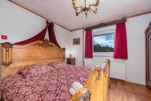een slaapkamer met een bed met rode gordijnen en een raam bij Magnus Lupus in Korenica
