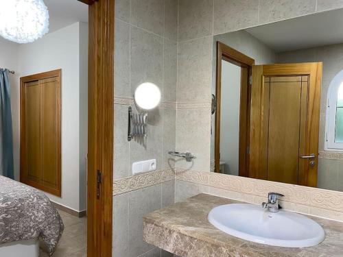 a bathroom with a sink and a bed and a mirror at Comfortable family house with pool and jacuzzi in Costa de Antigua
