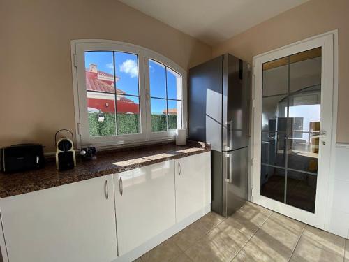 a kitchen with white cabinets and a large window at Comfortable family house with pool and jacuzzi in Costa de Antigua