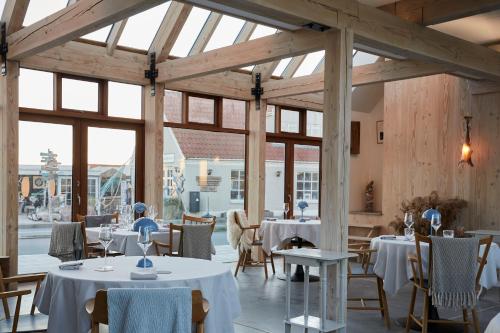 a dining room with tables and chairs and windows at Vesterlandet in Vestervig