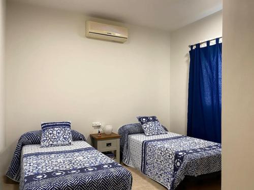 1 dormitorio con 2 camas y una ventana con cortinas azules en Comfortable family house with pool and jacuzzi, en Costa de Antigua