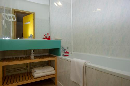 a bathroom with a sink and a tub and a mirror at Résidence Capfun Couleurs Soleil, Oz en Oisans in Oz