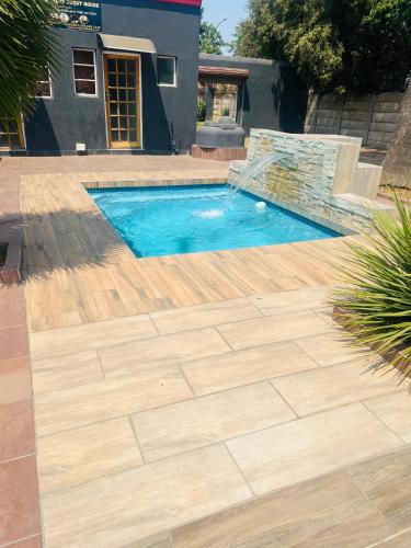 a swimming pool in a yard with a wooden deck at Royal Nest Guest House in Vereeniging