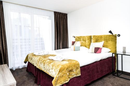 1 dormitorio con 1 cama grande con colcha de oro en HOF HOTEL, en Kaunas