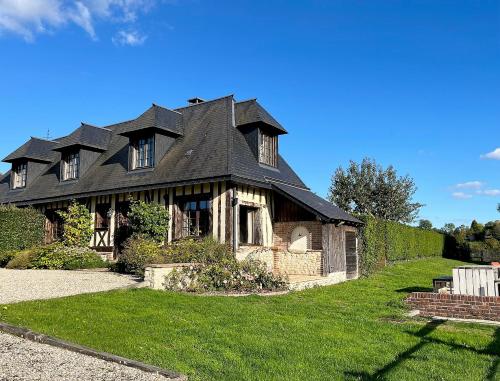 une maison ancienne avec un toit noir sur une pelouse verte dans l'établissement Le Gîte Marguerite - Calvados : vue panoramique sur la Normandie, à Hermival-les-Vaux