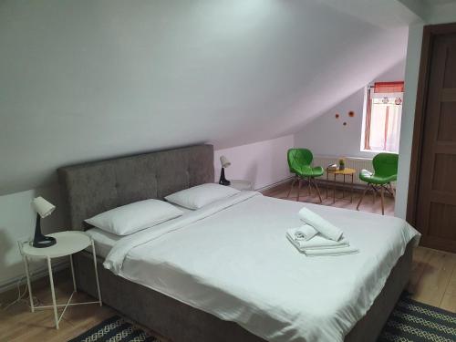 a bedroom with a bed and two green chairs at Casa Saga in Gura Humorului